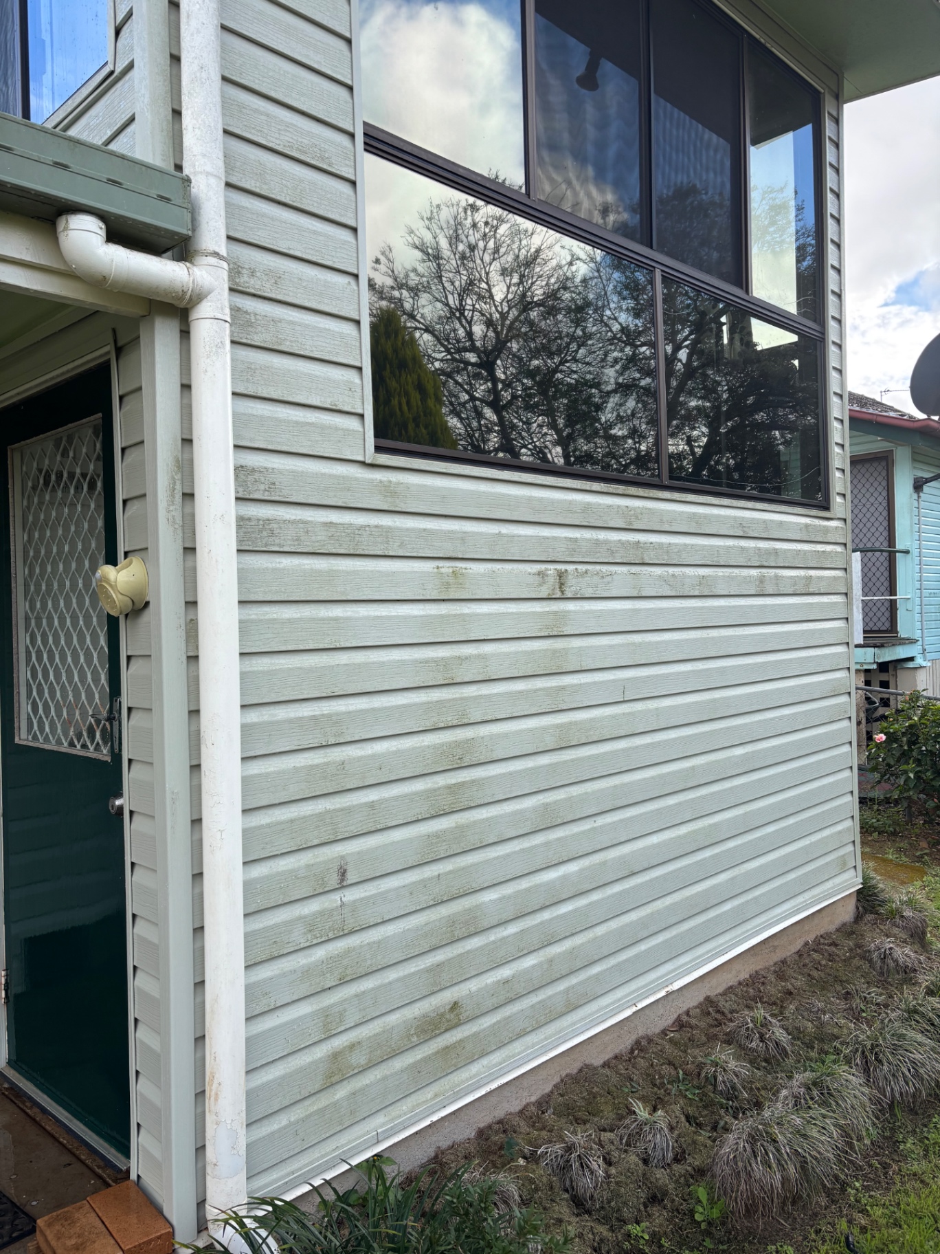 Mould and grime soft washed off weatherboard cladding. — before